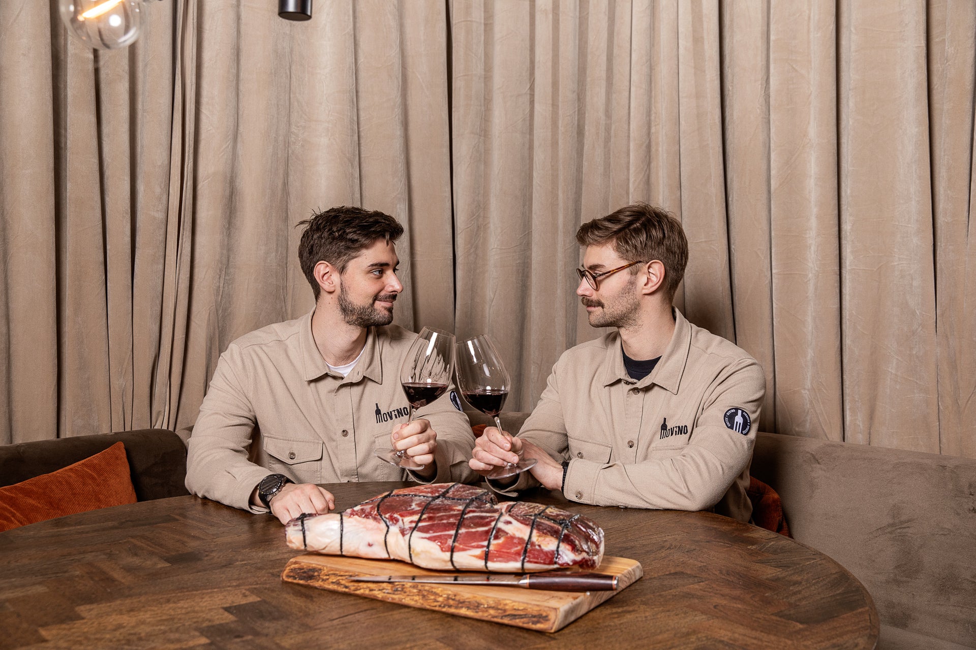 To værter ved bordet med vin og mad hos Movino
